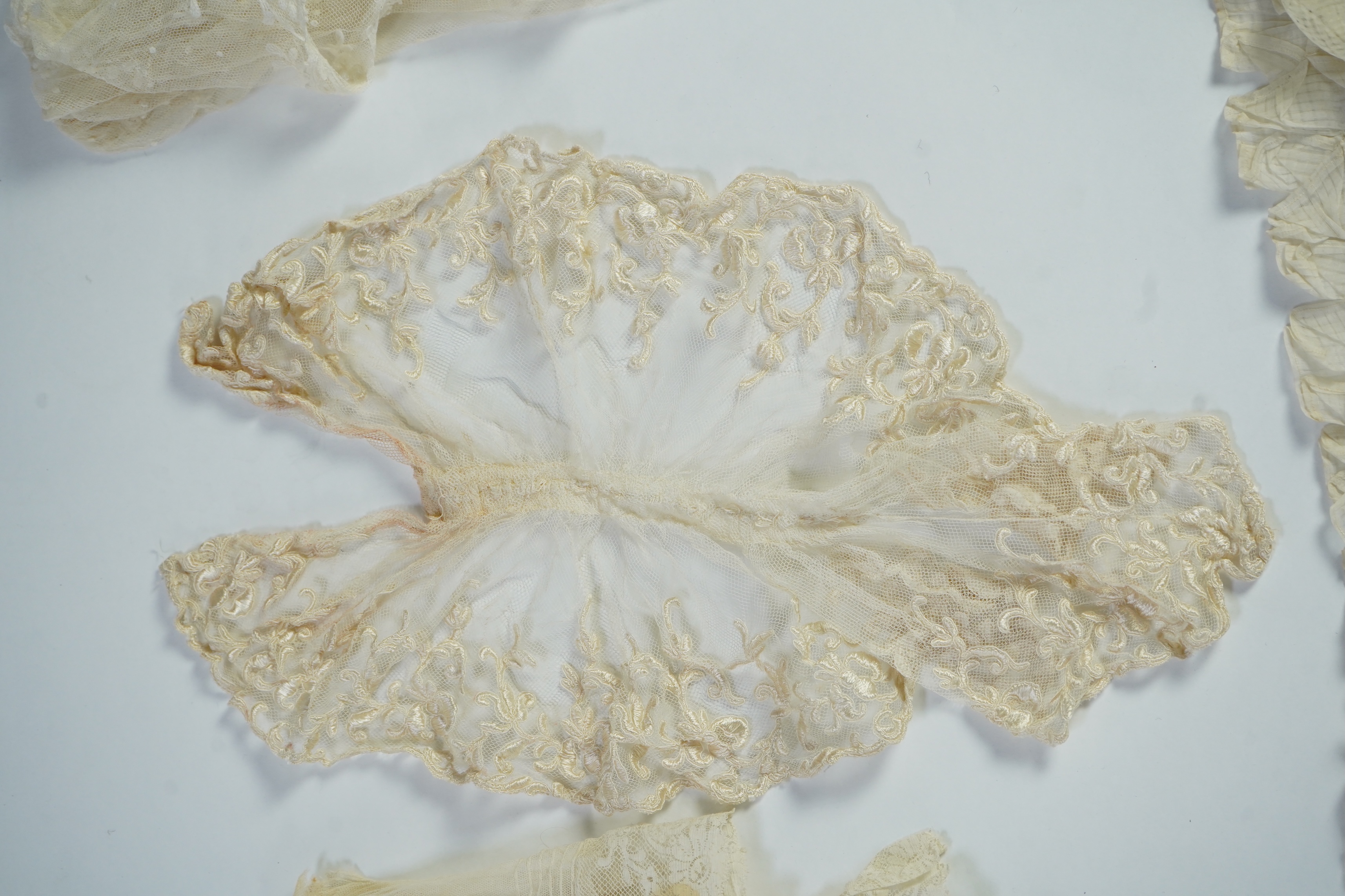 A suitcase containing a cream silk lace skirt to a dress, an Edwardian silk petticoat and various collars, possibly for theatrical use, silk petticoat 96 cm long. Condition - fair